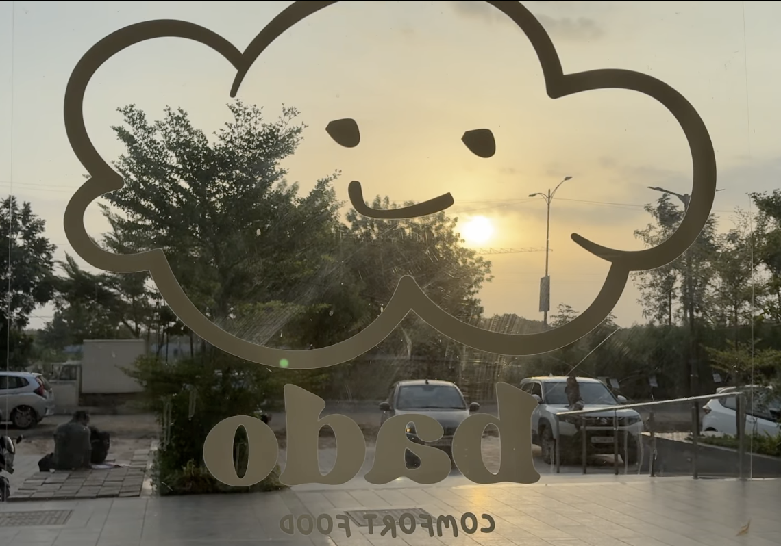 Bado storefront — cloud mascot etched on the glass with a golden sunset behind
