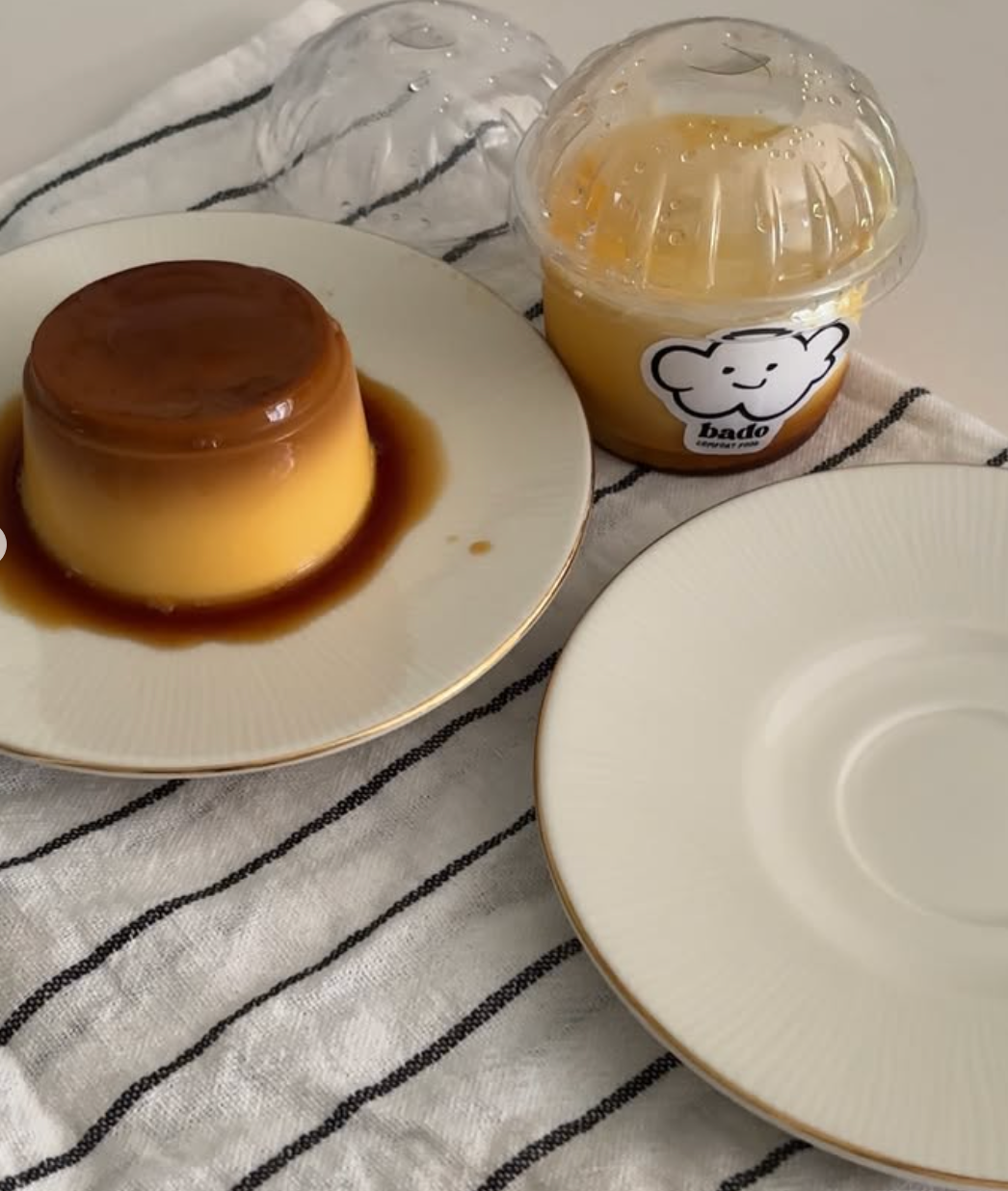 Japanese custard pudding with caramel on a white plate beside a Bado pudding cup