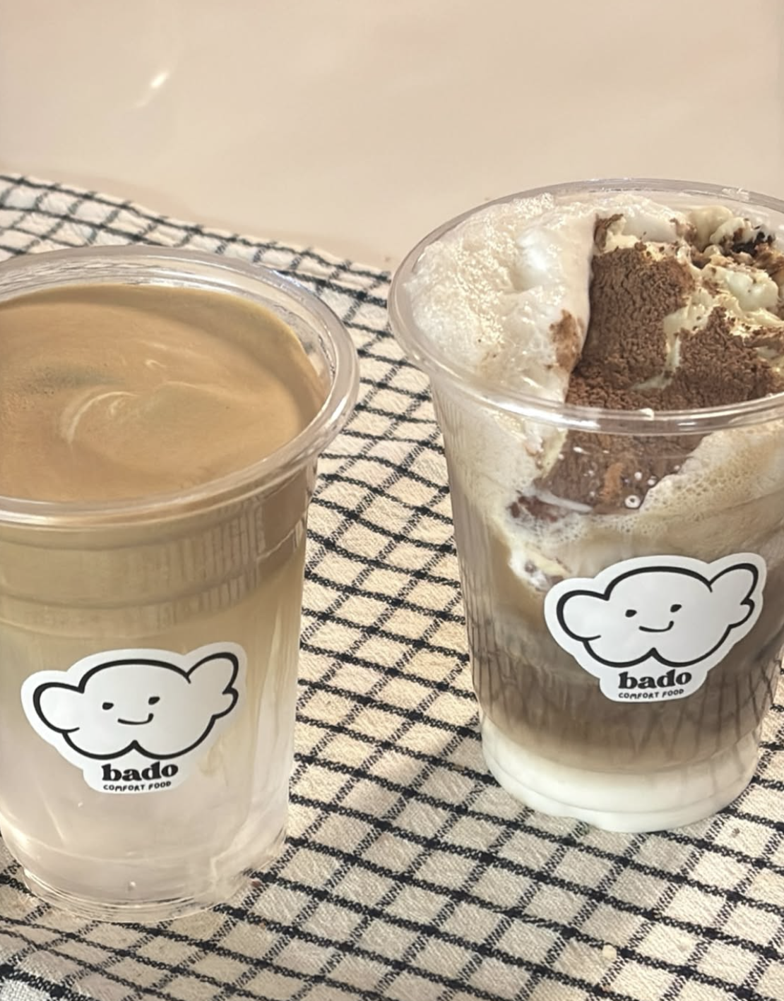Two Bado iced cloud coffees in branded cups on a diamond-pattern cloth